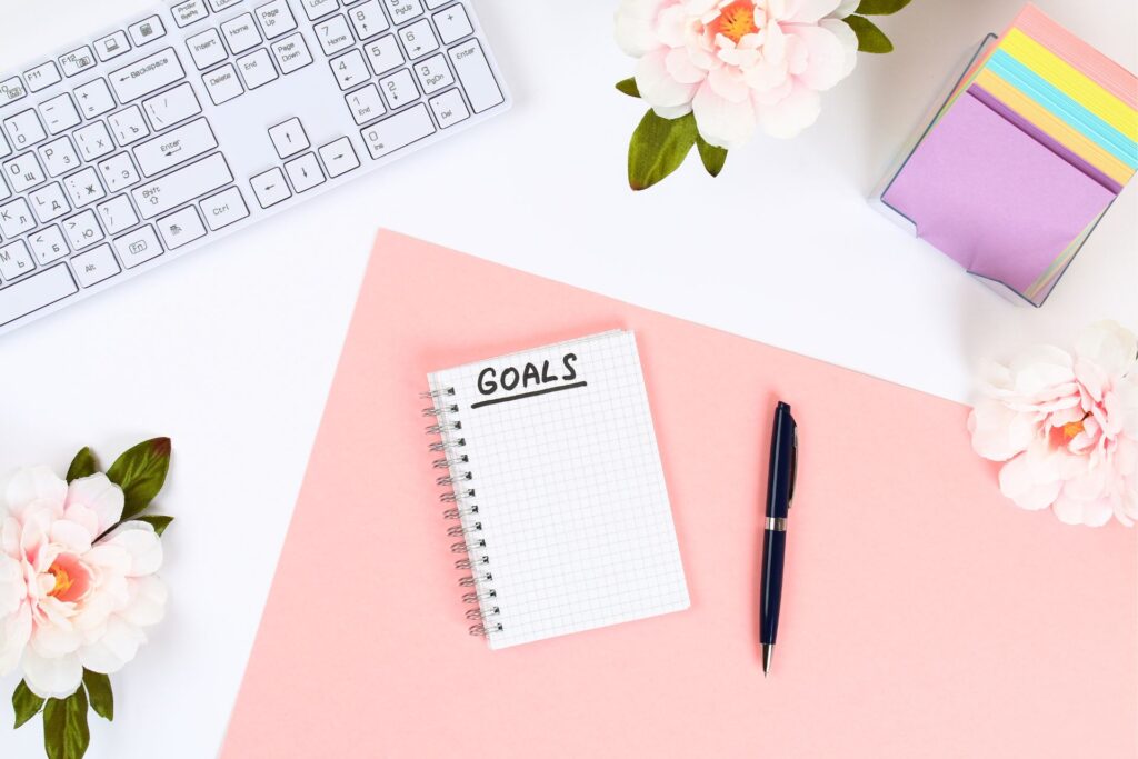 how to overcome the fear of starting your own business action step number 4 - set your goals. a desk with an open notebook with goals written on it